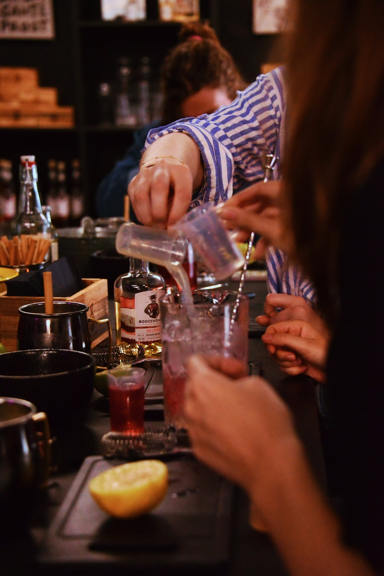 Deelnemer schenkt een roze cocktail uit een jigger in een mixing glass